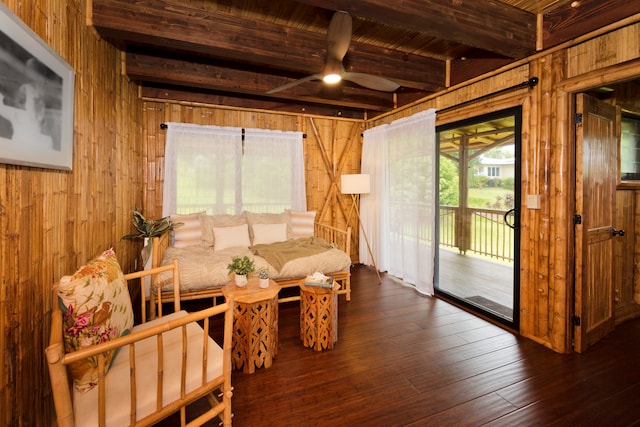 living room featuring beamed ceiling, dark hardwood / wood-style flooring, and wooden walls