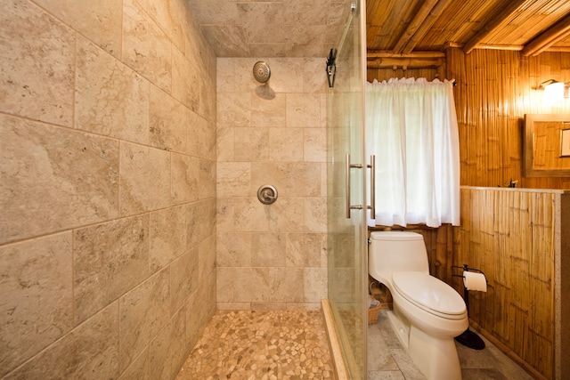 bathroom with wood walls, a tile shower, and toilet