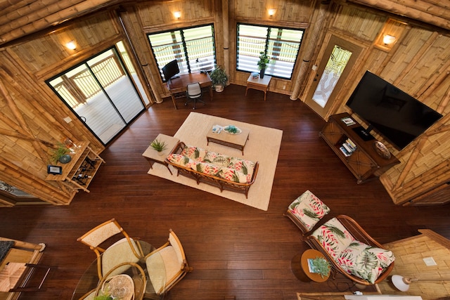 unfurnished living room with dark hardwood / wood-style floors, high vaulted ceiling, beam ceiling, and wooden walls