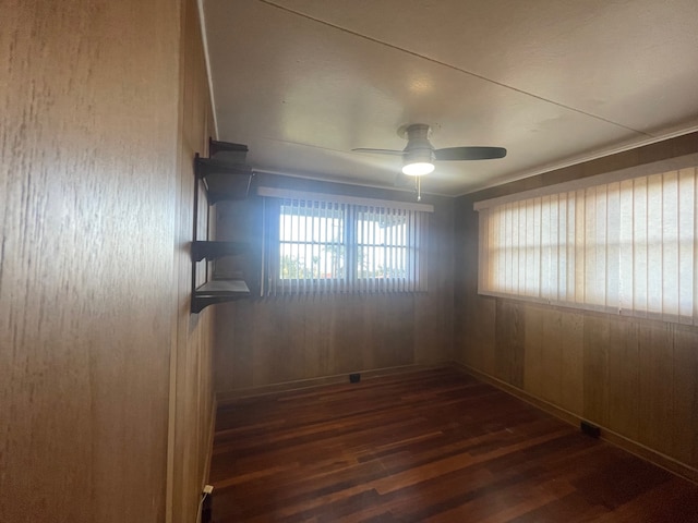 unfurnished room featuring dark hardwood / wood-style flooring, wooden walls, and ceiling fan