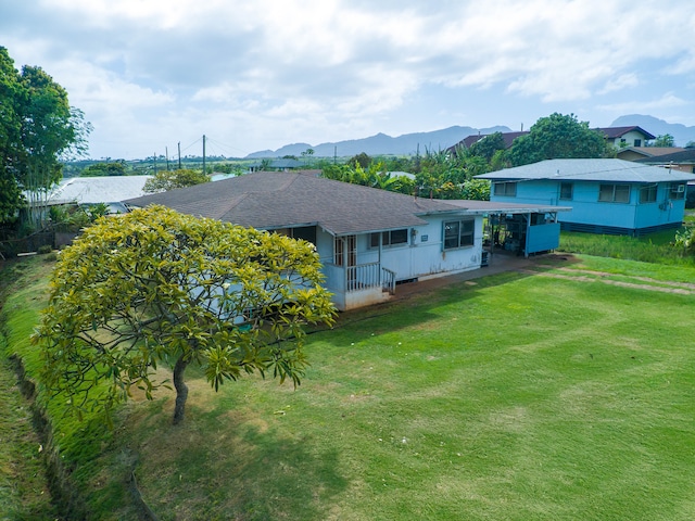 back of property with a mountain view and a lawn