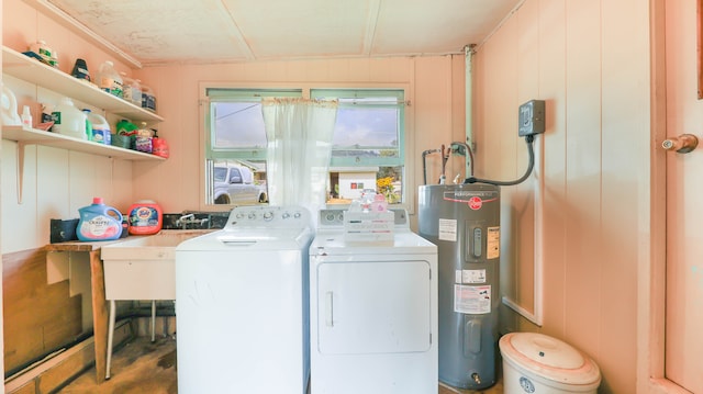 clothes washing area featuring wood walls, water heater, and washer and dryer