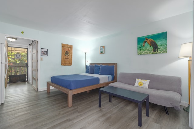 bedroom featuring white fridge and hardwood / wood-style floors