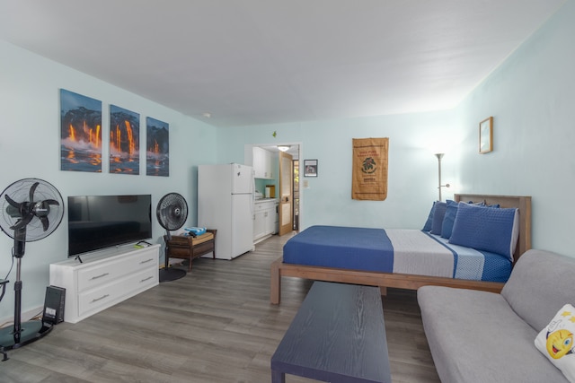 bedroom with ensuite bathroom, light hardwood / wood-style flooring, and white fridge