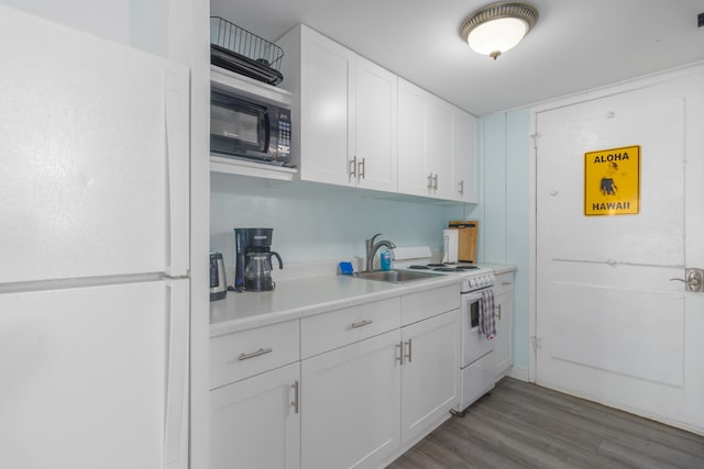 kitchen with white appliances, sink, light hardwood / wood-style flooring, and white cabinetry