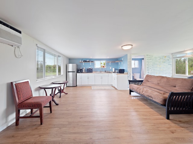 living room featuring light hardwood / wood-style flooring, sink, and an AC wall unit