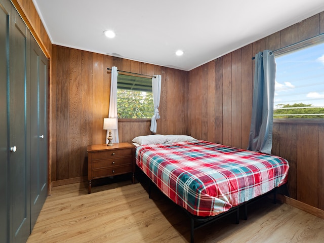 bedroom featuring light hardwood / wood-style flooring, wooden walls, and a closet