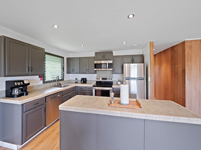 kitchen with appliances with stainless steel finishes, light wood-type flooring, sink, and a center island