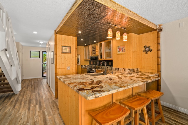 kitchen with sink, wooden walls, hardwood / wood-style floors, and a textured ceiling