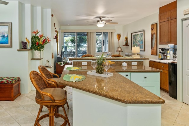 kitchen with ceiling fan, a center island, and light tile patterned floors