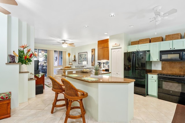 kitchen featuring stone counters, kitchen peninsula, a breakfast bar area, light tile patterned floors, and black appliances