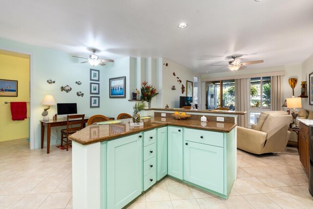 kitchen featuring green cabinets, ceiling fan, dark stone countertops, and light tile patterned floors