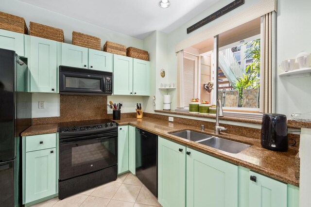 kitchen with dark stone countertops, sink, light tile patterned floors, and black appliances