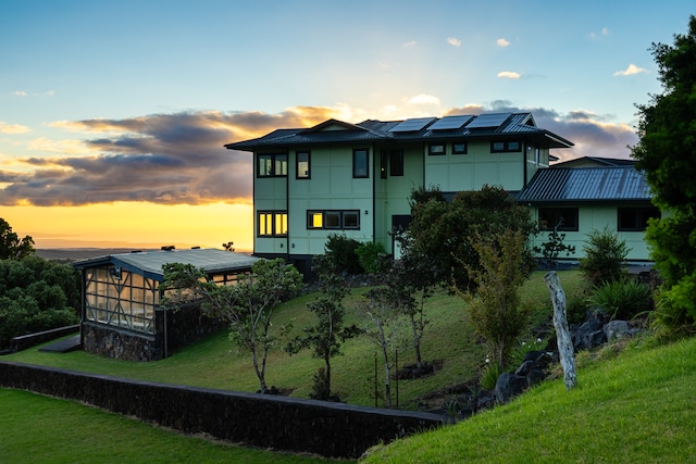 back house at dusk with a lawn