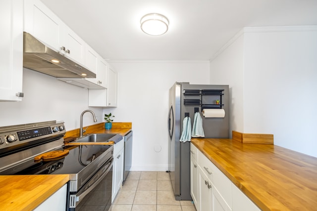 kitchen with stainless steel appliances, butcher block countertops, sink, and light tile patterned floors