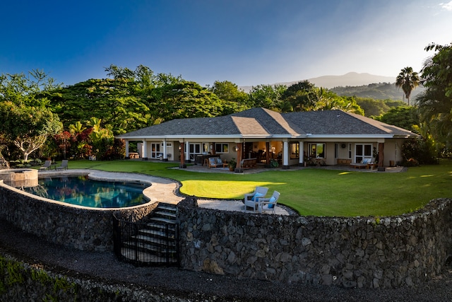 rear view of house with a lawn, a patio, and a mountain view