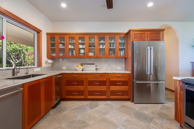 kitchen with light stone countertops, stainless steel appliances, sink, and tasteful backsplash