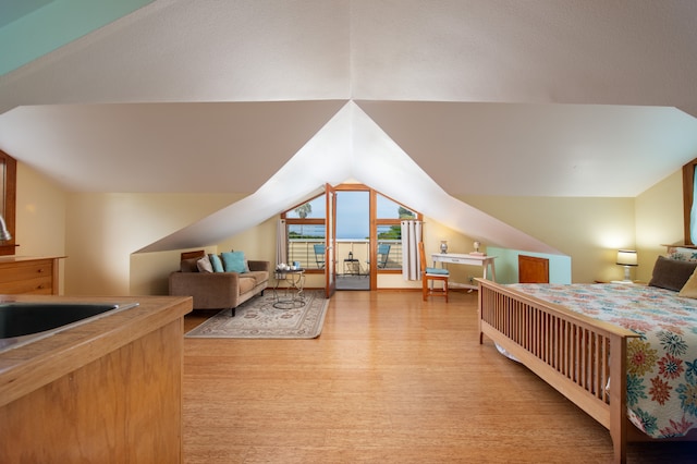 bedroom with light hardwood / wood-style floors, lofted ceiling, and sink