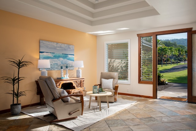 living area with a healthy amount of sunlight and a tray ceiling