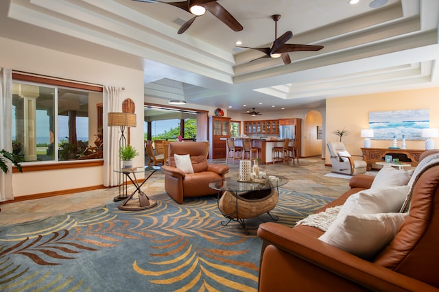 living room with ceiling fan and a raised ceiling