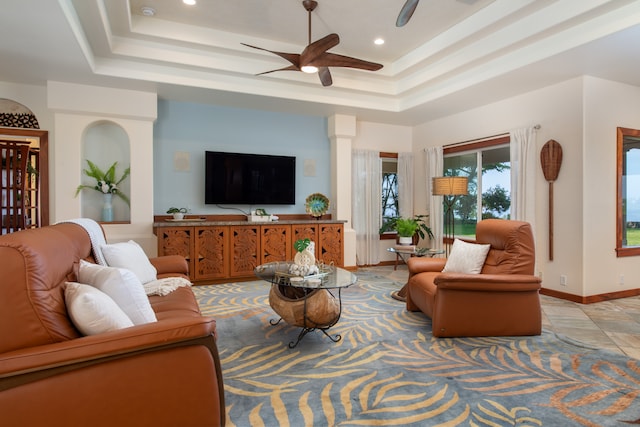 living room featuring a tray ceiling and ceiling fan