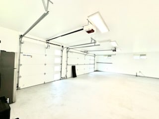 garage with a garage door opener and stainless steel fridge