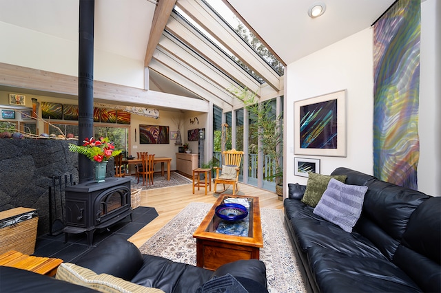 living room with high vaulted ceiling, hardwood / wood-style floors, and a wood stove