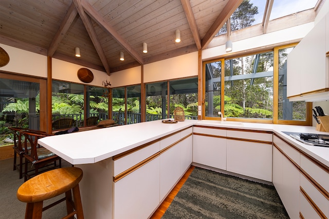 kitchen featuring kitchen peninsula, white cabinets, a breakfast bar area, and wood-type flooring