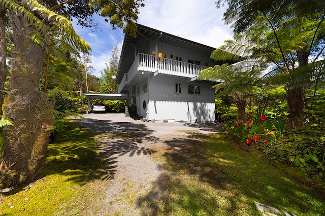 view of home's exterior with a carport, a balcony, and a lawn