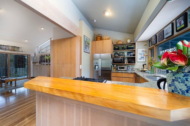 kitchen with hardwood / wood-style floors, butcher block countertops, kitchen peninsula, vaulted ceiling, and stainless steel fridge with ice dispenser