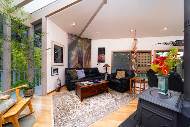 living room featuring a skylight, light wood-type flooring, and a wood stove