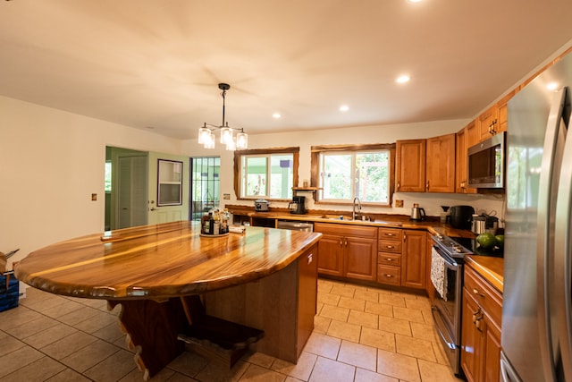 kitchen with stainless steel appliances, a center island, decorative light fixtures, sink, and a chandelier