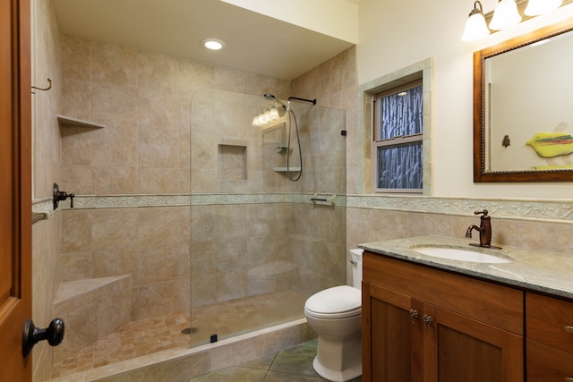 bathroom featuring tile walls, tile patterned floors, a tile shower, vanity, and toilet