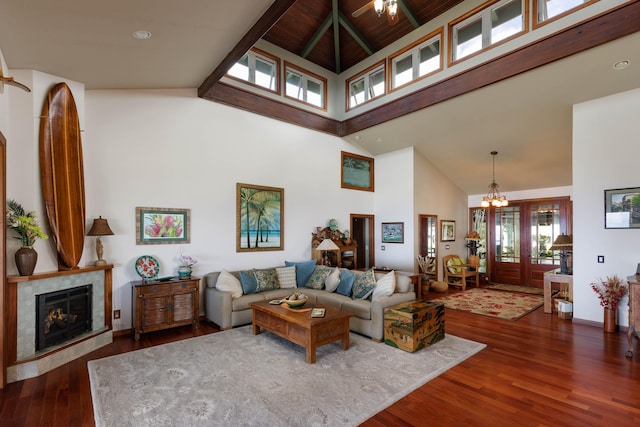 living room featuring high vaulted ceiling, wood finished floors, a chandelier, a fireplace, and beam ceiling