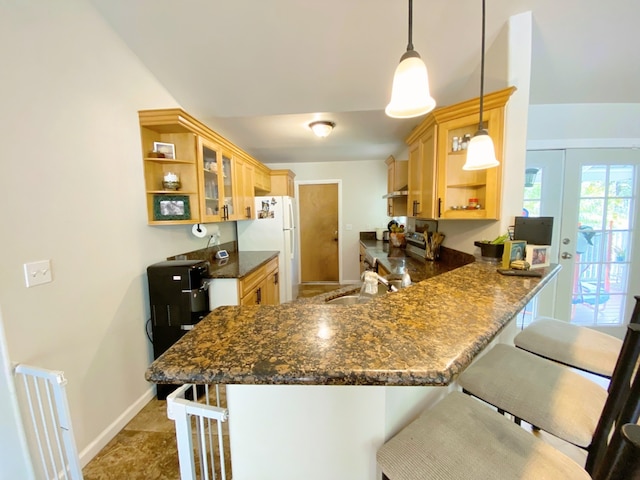 kitchen with hanging light fixtures, sink, kitchen peninsula, a kitchen breakfast bar, and dark stone countertops