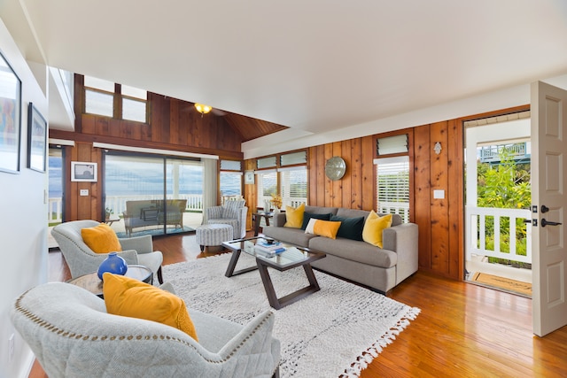 living room featuring wooden walls, lofted ceiling, and light hardwood / wood-style floors