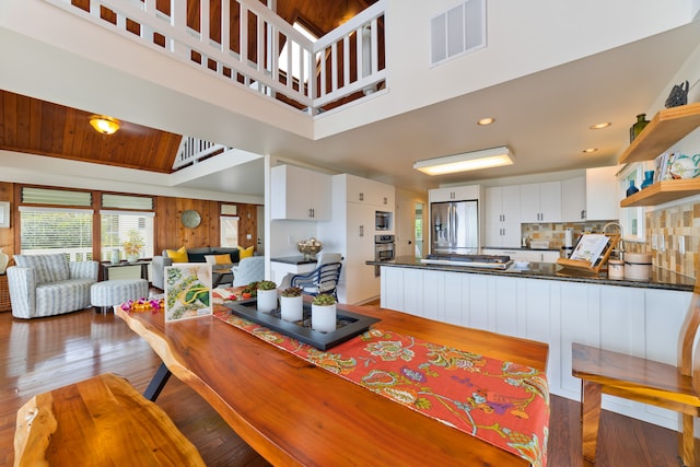 dining area with wooden ceiling, a towering ceiling, and light hardwood / wood-style flooring