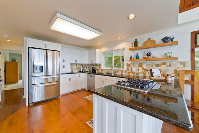 kitchen with stainless steel appliances, light wood-type flooring, backsplash, white cabinets, and kitchen peninsula