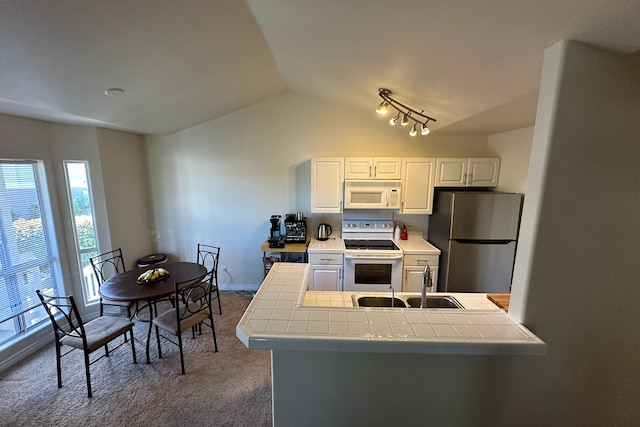 kitchen featuring lofted ceiling, white appliances, sink, white cabinetry, and tile countertops