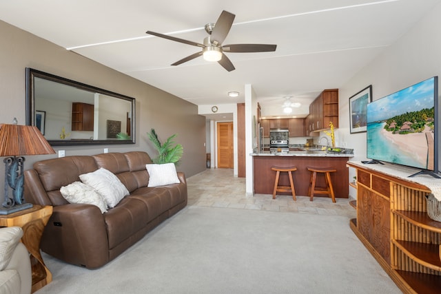 living room with sink, light carpet, and ceiling fan