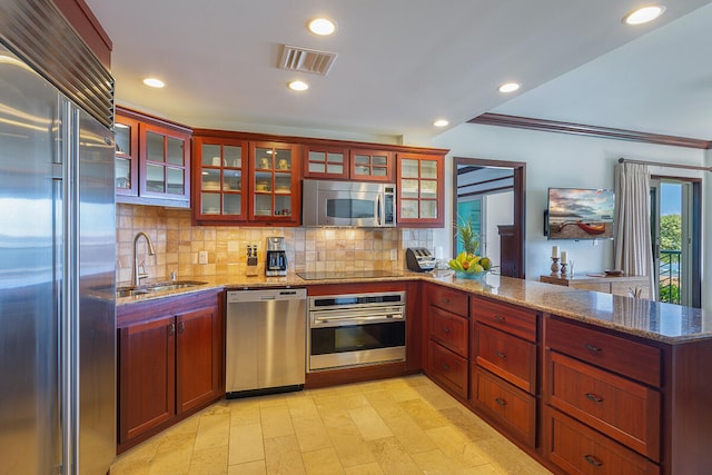 kitchen with sink, kitchen peninsula, appliances with stainless steel finishes, light stone countertops, and crown molding