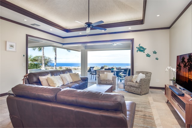 living room with ceiling fan, light tile patterned flooring, ornamental molding, and a tray ceiling