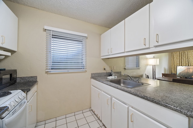 kitchen featuring white cabinetry, sink, light tile patterned floors, and white stove