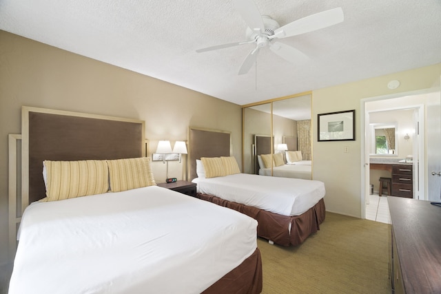 bedroom with a closet, ceiling fan, carpet flooring, and a textured ceiling