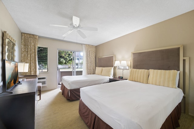 carpeted bedroom featuring a wall unit AC, a textured ceiling, and ceiling fan