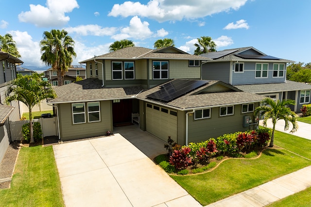 view of front of home featuring a garage, solar panels, and a front yard