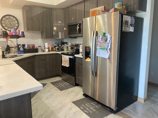 kitchen with stainless steel appliances, dark brown cabinets, and sink