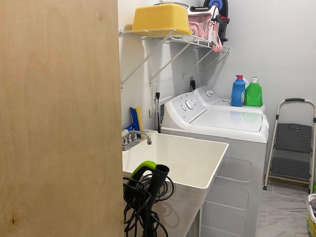 laundry room with washing machine and dryer, marble finish floor, a sink, and laundry area
