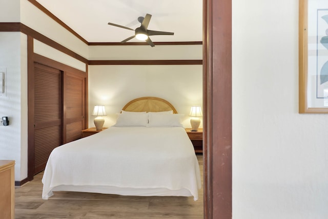 bedroom featuring ceiling fan, a closet, crown molding, and light hardwood / wood-style flooring