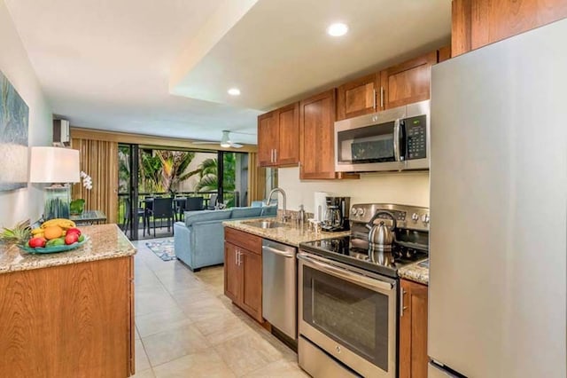 kitchen featuring sink, appliances with stainless steel finishes, light stone counters, and light tile patterned floors